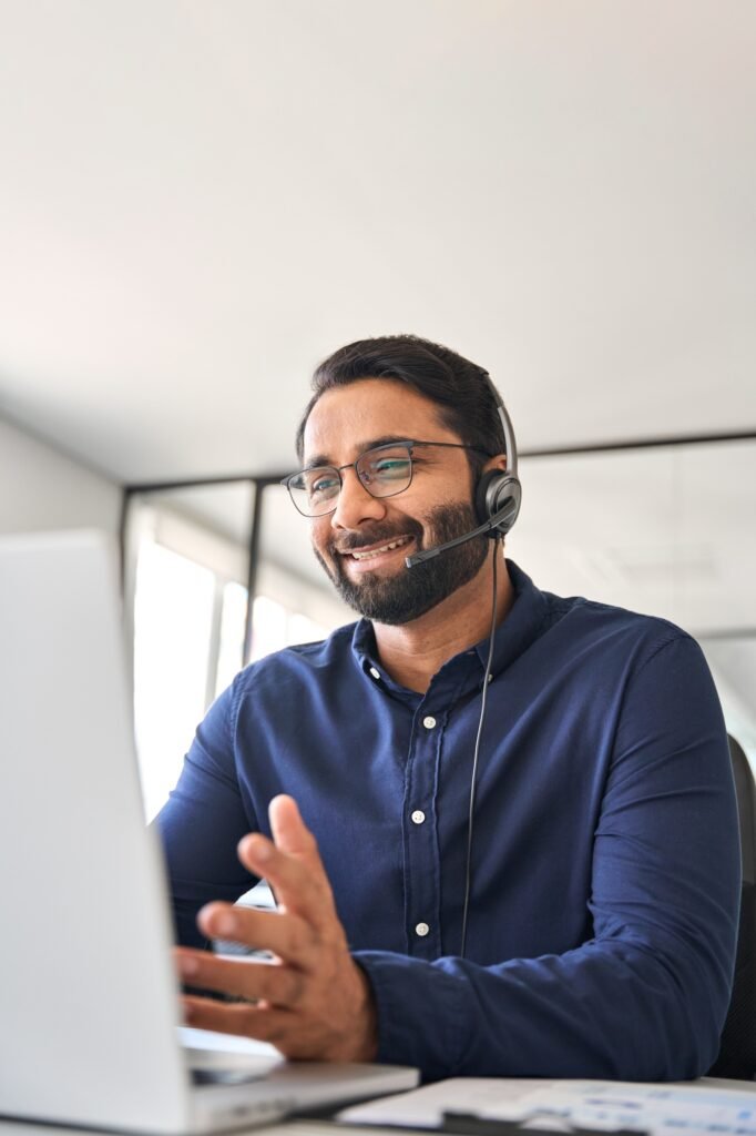 Happy Indian call center agent in headset working in customer support office.